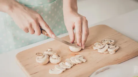 Woman cutting mushrooms in kitchen